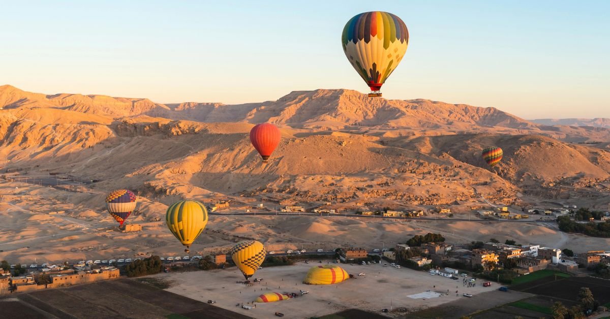 Hot air balloons flying above Luxor West Bank at sunrise